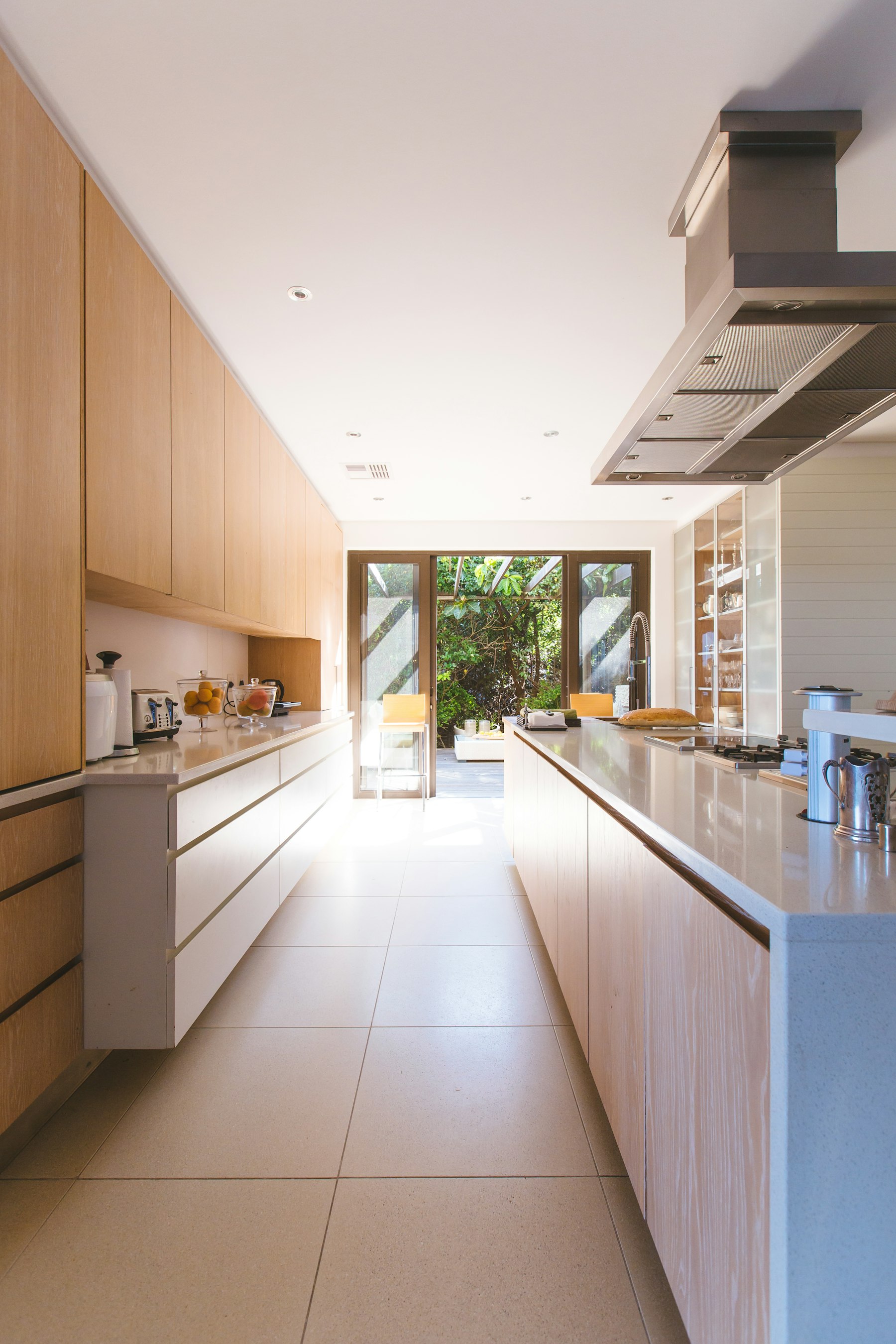 Sunlit modern kitchen with light wood cabinetry and open patio doors